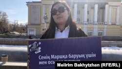 Участница одиночного пикета за Женский марш в Алматы Жамиля Касымхан держит плакат с надписью: «Я стою здесь, чтобы ты пошла на Марш». 23 февраля 2023 года