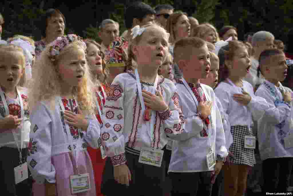 Schoolgirls sing Ukraine&#39;s national anthem as they attend a ceremony for the first day of school in Bucha, near Kyiv.