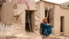 An Afghan woman sits in front of a damaged house after flash floods hit the Madrasa village in Ghor Province on May 24.