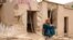 An Afghan woman sits in front of a damaged house after flash floods hit the Madrasa village in Ghor Province on May 24.