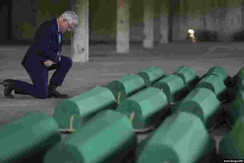 U.S. Ambassador to Bosnia-Herzegovina Michael Murphy kneels next to the coffins containing the remains of the newly identified victims.