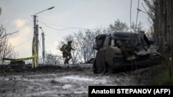 Ukrán katona keres fedezéket Bahmutban a frontvonalon 2023. április 23-án