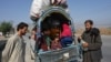 Afghan nationals along with their families stand along a road west of Peshawar, Pakistan, on October 6.