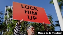  Докато съдът изслушваше Тръмп пред съда в Маями имаше както протестиращи против него, по този начин и поддръжници на някогашния президент.Доминик Сантана държи афиш с надпис 