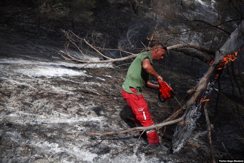 Një pjesëtar ushtarak i shërbimeve emergjente duke punuar për të shuar një zjarr të egër afër fshatit Cakran, në Qarkun e Fierit.