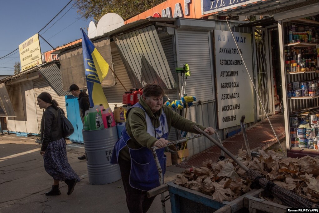 La gente passa davanti a una bandiera ucraina in un mercato il 29 ottobre. Prokudin ha anche riferito che una persona è stata uccisa e 16 persone sono rimaste ferite mentre Kherson è stato colpito da 36 colpi durante la notte.   