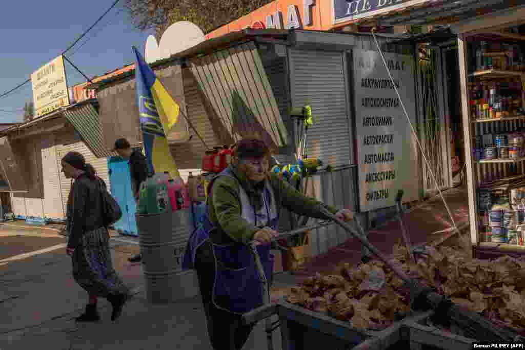 People walk past a Ukrainian flag at a market on October 29. Prokudin also reported that one person was killed and 16 people were injured as Kherson was fired upon 36 times overnight. &nbsp;