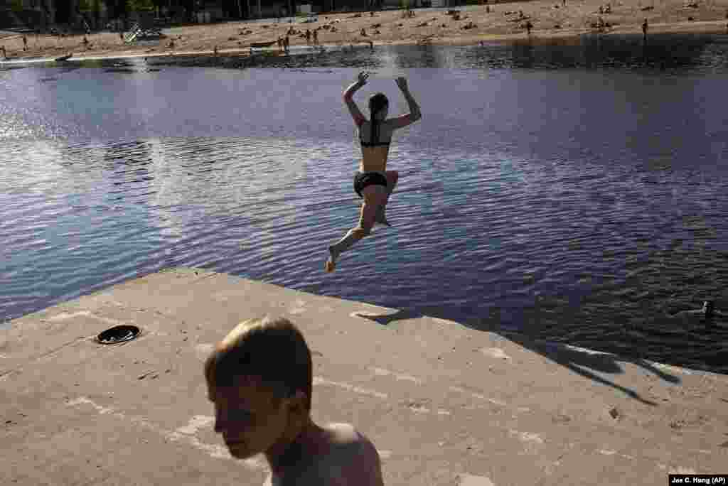 A girl jumps into the Dnieper River in Kyiv.