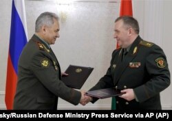 Ministrul rus al apărării Sergei Shoigu (în stânga) și omologul său din Belarus Viktor Khrenin schimbă documente, în cadrul reuniunii miniștrilor apărării din țările post-sovietice membre ale Organizației Tratatului pentru Securitate Colectivă, la Minsk, 25 mai.