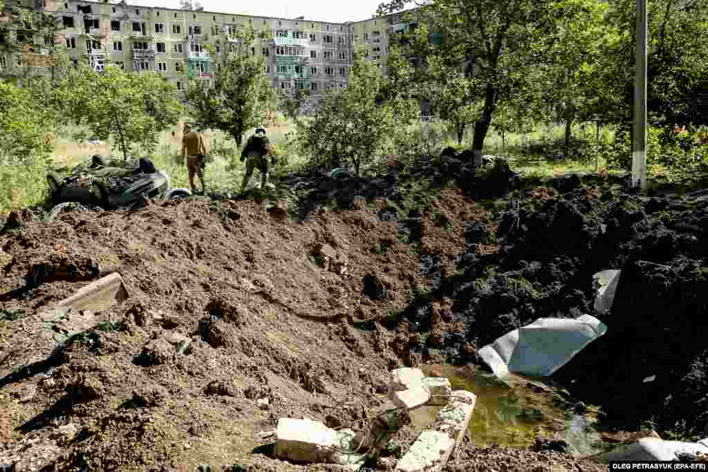 Several Ukrainian soldiers from the 72nd Mechanized Brigade walk past a shell crater in Vuhledar. A three-week confrontation near the town resulted in what Ukrainian officials say was the biggest tank battle of the war so far, with the Kremlin&#39;s forces reportedly taking heavy losses as Kyiv claimed it destroyed 130 tanks and armored personnel carriers. &nbsp;