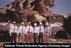 Unidentified staff of the U.S.-led disarmament program in front of a destroyed Tu-160.