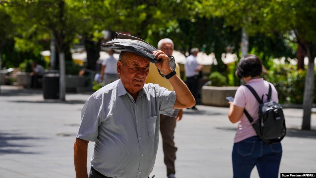 Mbrojtja e kokës nga dielli me çkado që të rastis në dorë. Prishtinë, 21 qershor 2024.
