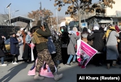 A member of the Taliban fires into the air to disperse Afghan women during a rally to protest restrictions on women in Kabul on December 2021.