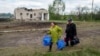 Люди йдуть зі своїми речами до пункту евакуації у Вільчі, поблизу Вовчанська, 12 травня 2024 року