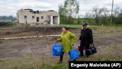 Люди йдуть зі своїми речами до пункту евакуації у Вільчі, поблизу Вовчанська, 12 травня 2024 року