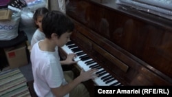 Cristian Andrei Iliescu plays the piano in his family’s temporary shelter.