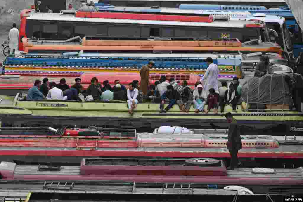 Passengers sit atop a bus waiting their departure at a bus station in Lahore.
