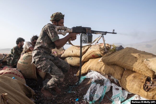 A Yemeni fighter backed by the Saudi-led coalition fires his weapon during clashes with Iran-backed Huthi rebels in Yemen in 2021.