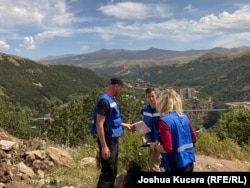 EUMA monitors Thomas Tartarin (center), Pekka Mattila (left), and Ema Stastna on a hill overlooking the Armenian resort town of Jermuk and, in the background, new military positions that Azerbaijan took during fighting in September 2022.