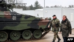 German Defense Minister Boris Pistorius (right) walks past a Marder infantry fighting vehicle type at a training center in Munster, northern Germany, on February 20. 