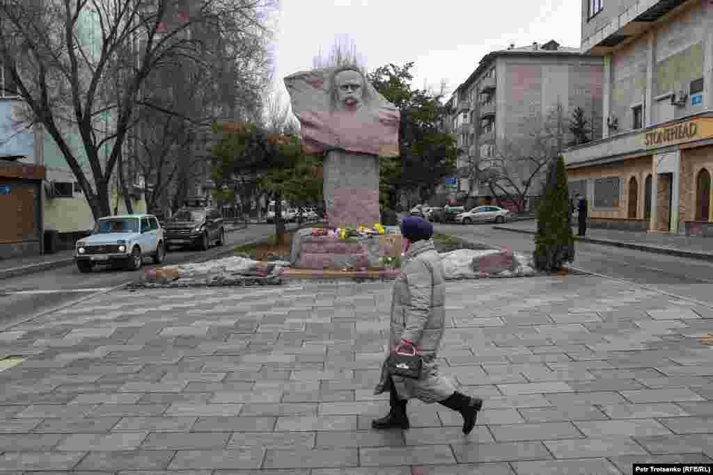 Женщина проходит мимо памятника Тарасу Шевченко, к которому люди только начали приносить цветы в память о погибших украинцах &nbsp;