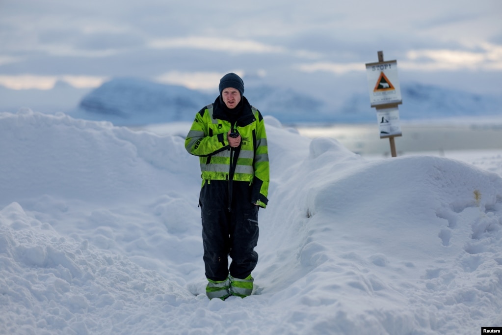 Rojtari i Kings Bay AS, Jakob Weiset, 31 vjeç, përdor radion e tij përpara një shenje paralajmëruese të ariut polar që shënon zonën e sigurt të vendbanimit në Ny-Aalesund, Norvegji, 11 prill 2023.