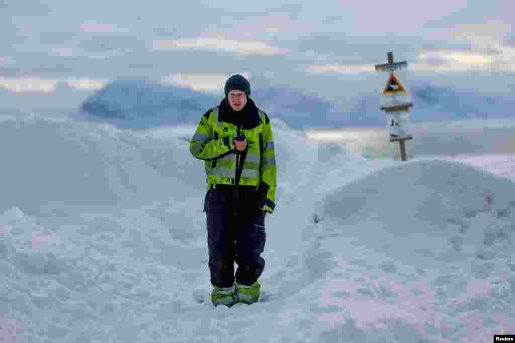 Rojtari i Kings Bay AS, Jakob Weiset, 31 vjeç, përdor radion e tij përpara një shenje paralajmëruese të ariut polar që shënon zonën e sigurt të vendbanimit në Ny-Aalesund, Norvegji, 11 prill 2023.