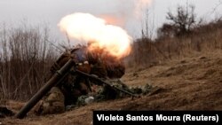 Ukrainian troops take cover as they fire a mortar shell at a frontline position near Bakhmut on March 16. 