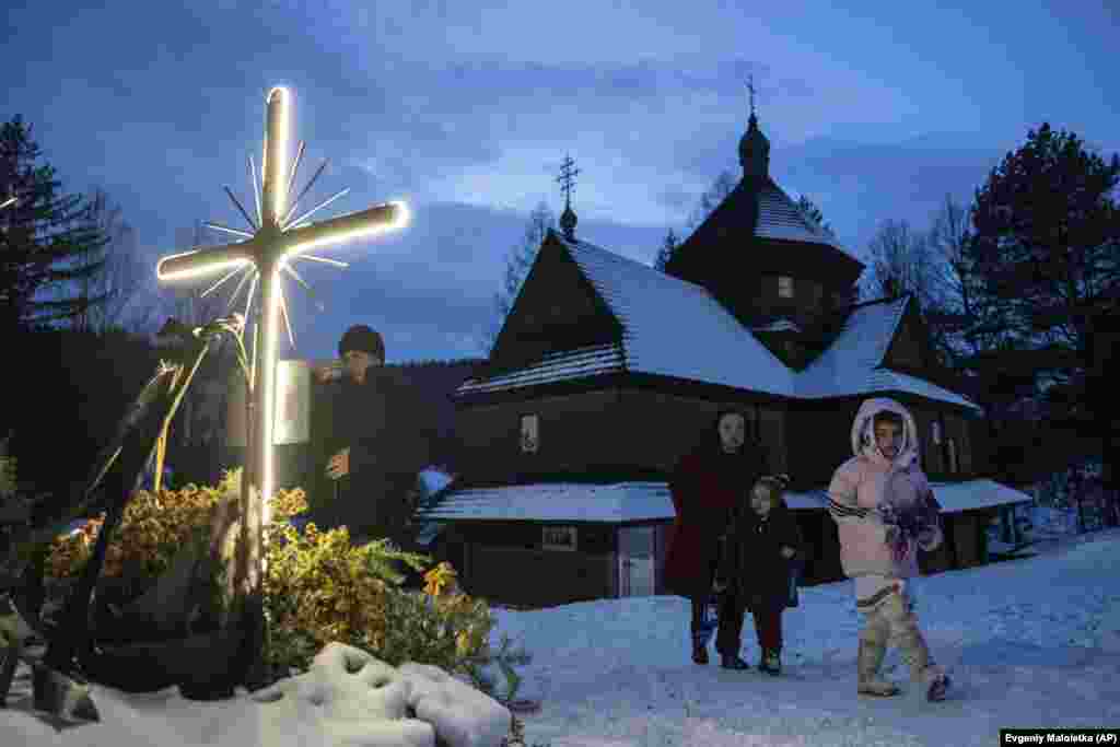 O femeie și copiii ei se îndreaptă spre casă după slujba religioasă de Crăciun în satul Krivorivnia din vestul Ucrainei.