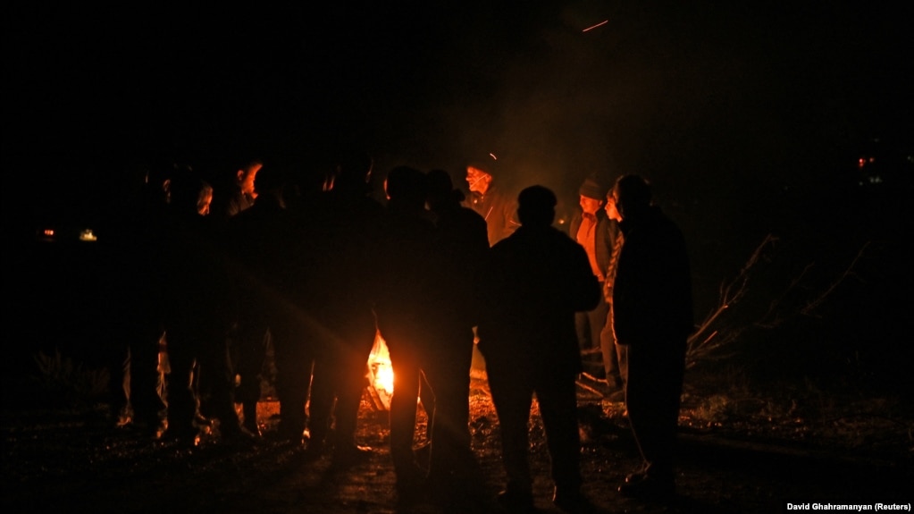 Refugjatët duke u ngrohur pranë një zjarri të ndezur në rrugën që çon drejt kufirit me Armeninë, derisa presin që të hapet rruga për në Armeni më 25 shtator. Armenia dhe Azerbajxhani kanë luftuar dy luftëra në tri dekadat e fundit lidhur me kontrollin e rajonit, i cili u bë i banuar me shumicë etnike, brenda kufijve të njohur ndërkombëtarisht të Azerbajxhanit, pas kolapsimit të Bashkimit Sovjetik.