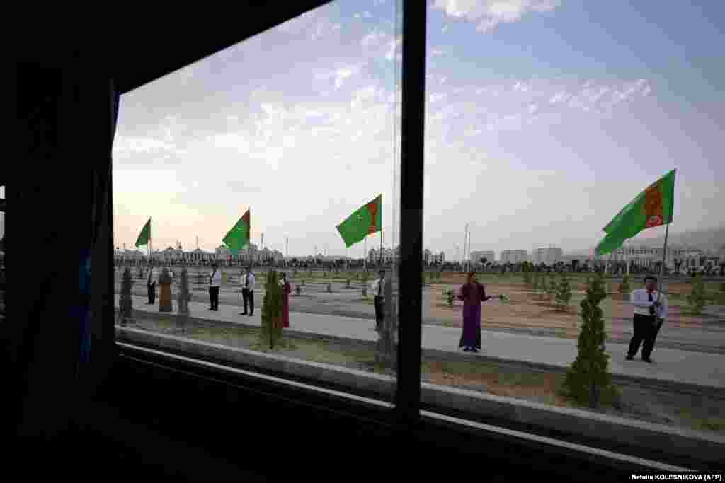 На другом снимке, сделанном из салона пресс-автобуса, запечатлены участники, держащие туркменские флаги на пути к новому городу. Бердымухамедов-старший управлял богатой газом страной с шестимиллионным населением в течение 15 лет до 2022 года. В стране построен сложный и даже причудливый культ его личности