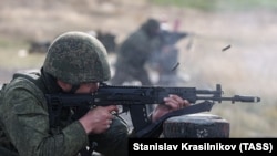 Російський військовослужбовець виконує елементи тактичної стрільби з автомата АК-12 під час військових навчань, 22 жовтня 2022 року