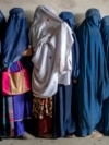 Afghan women wait to receive food rations distributed by a humanitarian aid group in Kabul in May 2023. 