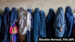 Afghan women wait to receive food rations distributed by a humanitarian aid group in Kabul in May 2023. 