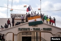 Mai mulți bărbați flutură steaguri ale Nigerului și Rusiei în sprijinul soldaților puciști în capitala Niamey/Niger, pe 3 august 2023.