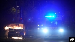 Линейка минава покрай горяща кола в Нантер, извън Париж.