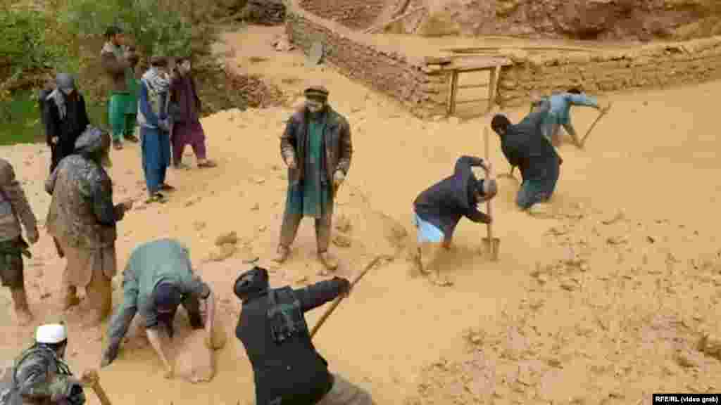 A video grab of Afghan men shoveling thick mud as they search for survivors and try to salvage their belongings in Baghlan Province.