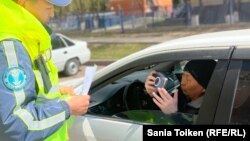 Активист Марат Жыланбаев (в машине) ведёт диалог с дорожным полицейским. Астана, 1 мая 2023 года