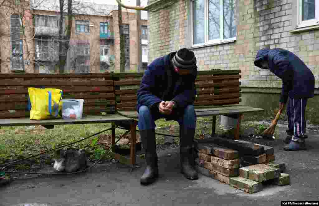 Civilians in Chasiv Yar clean near an improvised fireplace during a lull in shelling. With no electricity and water, residents must make do with what they can. &nbsp;