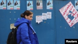 A woman walks past campaign posters for the parliamentary elections in Tehran.