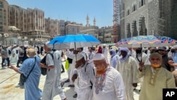 Hodočasnici drže kišobrane kako bi se zaštitili od vrućine dok odlaze nakon molitve ispred Velike džamije, tokom godišnjeg hadža u Meki, Saudijska Arabija, 12. juna 2024.