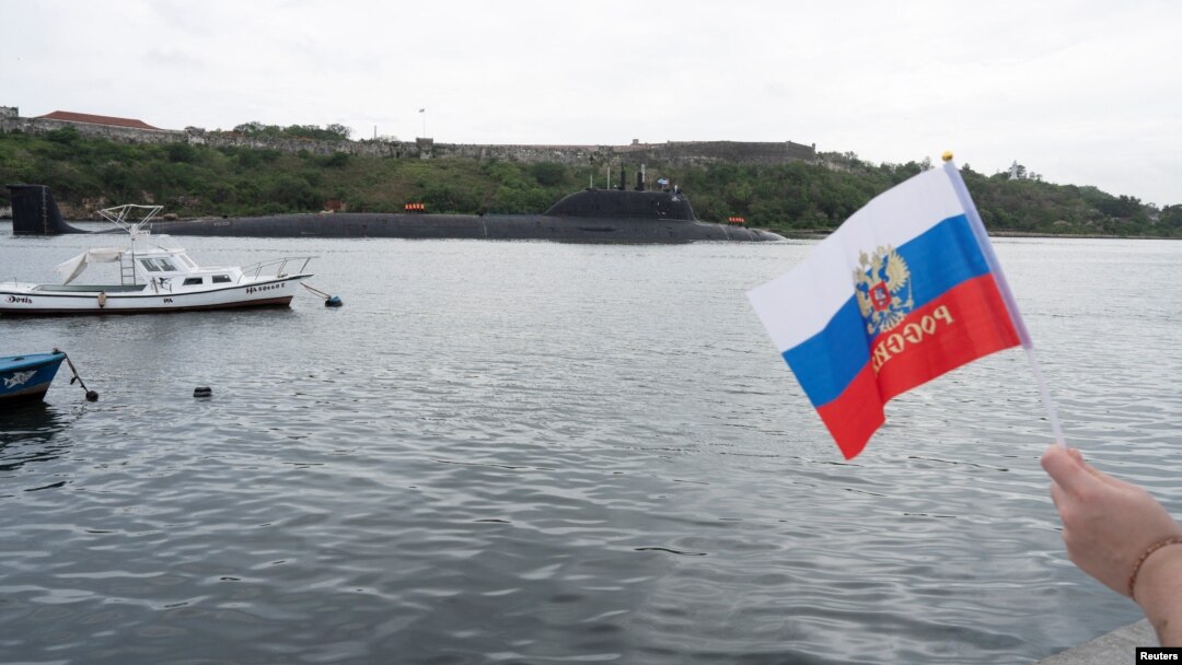 A member of Havana's Russian community held a flag as a Russian nuclear-powered submarine entered the bay of the Cuban capital in the last Russian naval visit, on June 12.