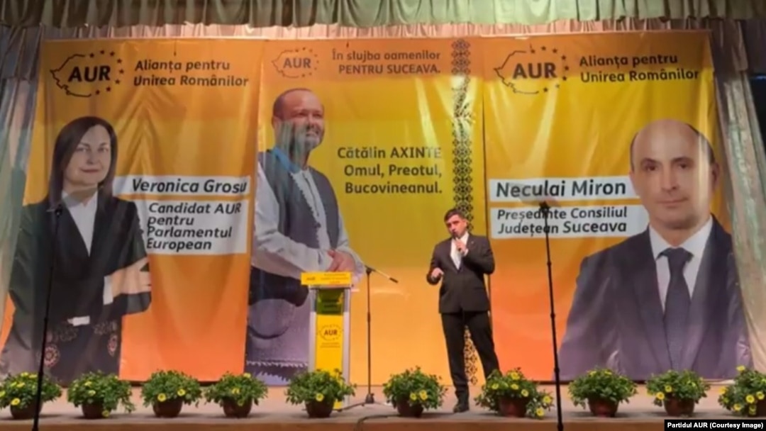 Pe scena Casei de Cultură din Suceava, președintele partidului AUR, George Simion, anunță candidatura preotului Cătălin Axinte la funcția de primar al orașului.