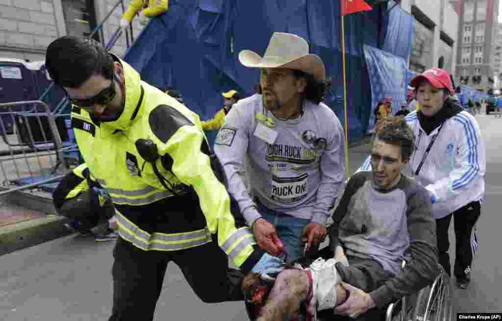 Hitna služba i volonteri guraju Jeffa Baumana u invalidskim kolicima nakon što je povrijeđen u jednoj od dvije eksplozije u blizini cilja.&nbsp;
