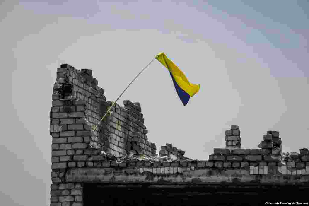 The Ukrainian national flag is seen above the rubble of a destroyed home in the newly liberated village of Neskuchne in the Donetsk region on June 13. Journalists were permitted entry to the village to show that Kyiv&#39;s forces have made gains in their counteroffensive against Russian forces.