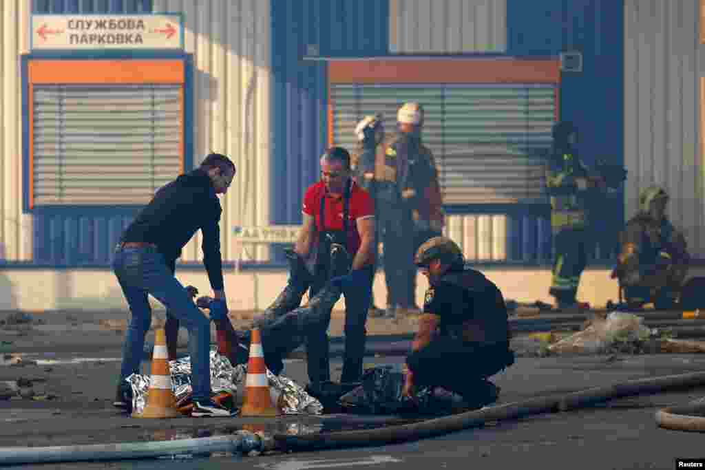 Працівник поліції оглядає тіло загиблого внаслідок атаки двох російських КАБ на гіпермаркет