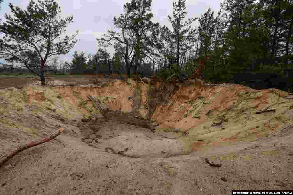 Imaginea 1: Un crater lăsat de bombă la periferia satului Teterivske. Imaginea 2: Urmele aceluiași crater. Mai multe zone din jurul Teterivske nu au fost încă curățate de echipele de geniști. &nbsp;