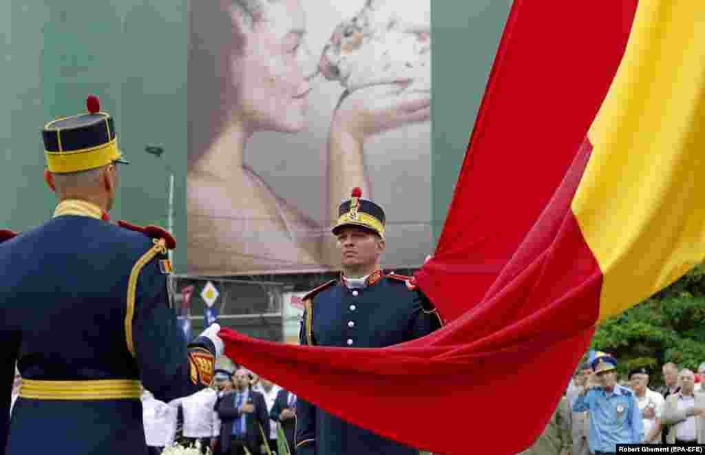 Romanian presidential honor guards raise a large national flag during a ceremony dedicated to National Flag Day in front of the National Military Circle building in downtown Bucharest on June 26.