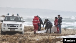 Rescue workers recover a body after a suspected migrant boat was shipwrecked off the coast of southern Italy. 