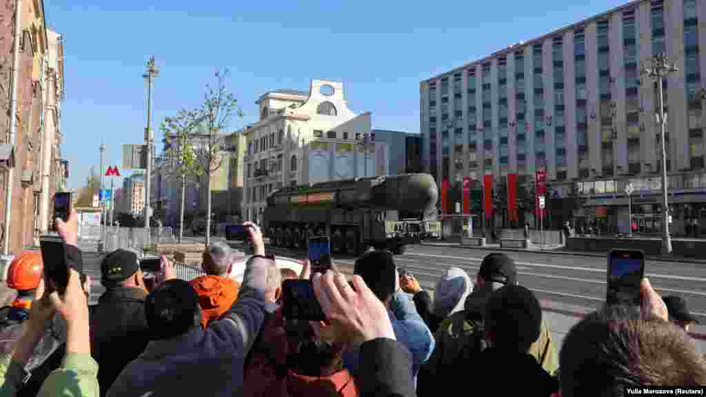 Moszkvaiak fotózkodnak a katonai parádéval kísért ünnepen, amelynek egyik eleme a hadieszközök bemutatója. A képen Jarsz rakétarendszerek és más páncélozott járművek haladnak el a nézők előtt